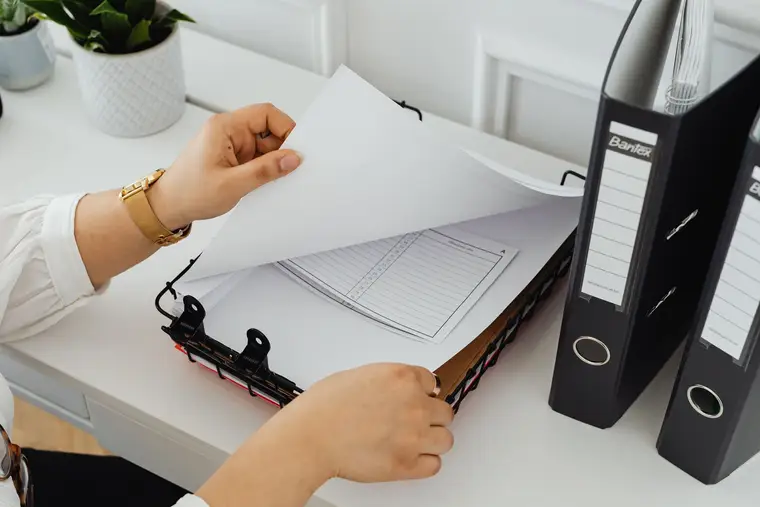 Ein Schreibtisch mitten in der Arbeit: Unterlagen, Ordner und ein Stempel